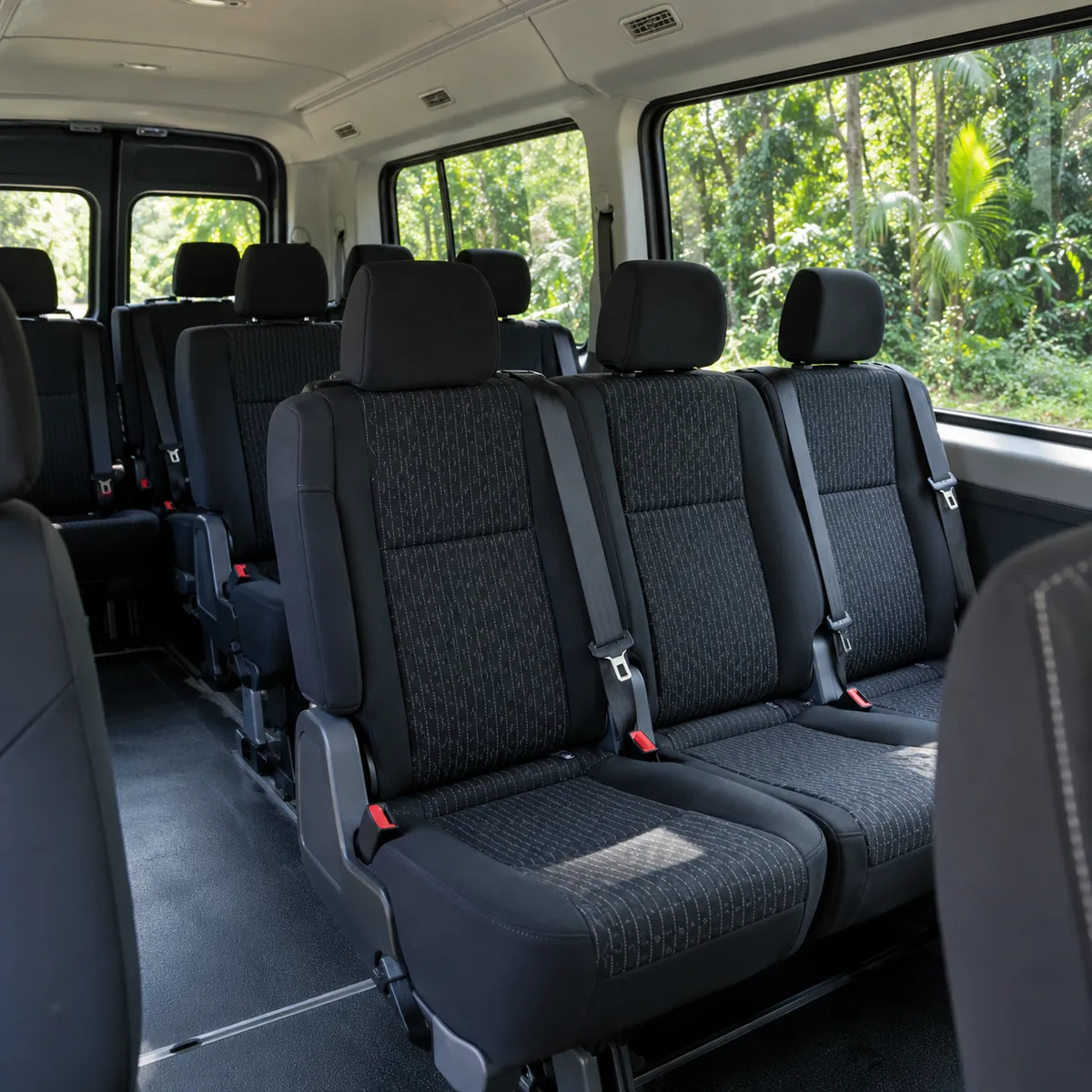 Interior de la camioneta con filas de asientos y ventanas a la selva